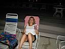 P1010018.jpg: Denise drinking Bud Light at the pool at night